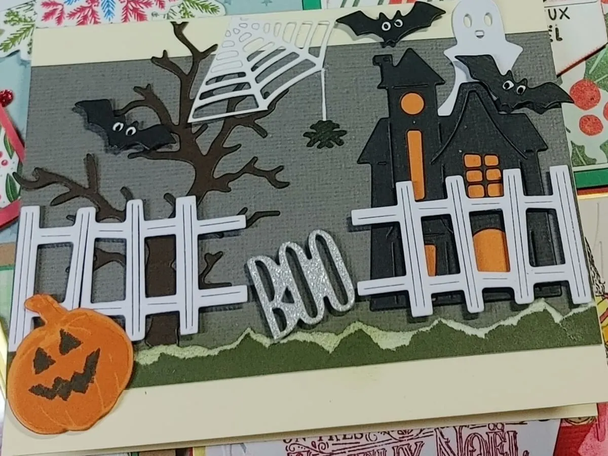 Photo d'une carte fait avec du collimage avec des motifs d'Halloween comme des citrouilles et une maison hantée
