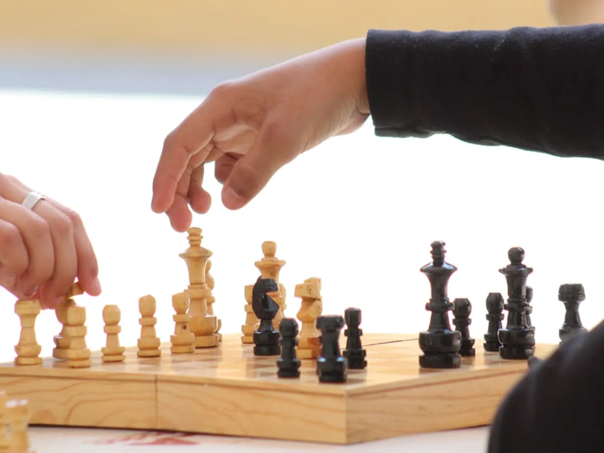 Les mains de 2 personnes qui déplacent des pièces sur un jeu d'échecs.