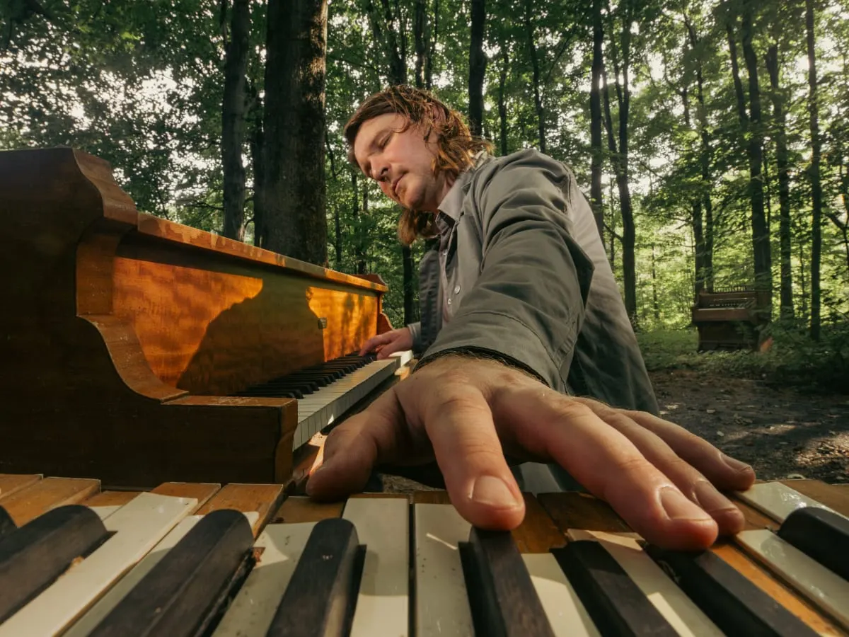 artiste Roman Zavada jouant du piano dans une forêt