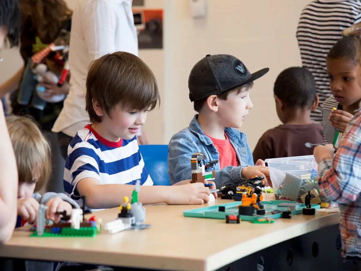 Plusieurs enfants attablés et jouant aux LEGOS.