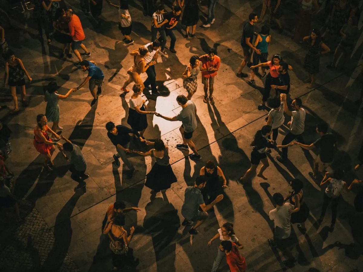 Photo de plusieurs personnes qui dansent en cercle dans une salle sombre