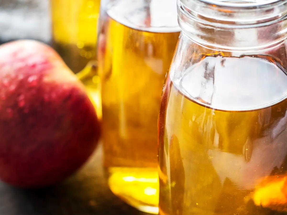 Des bouteilles de vinaigre de cidre et une pomme