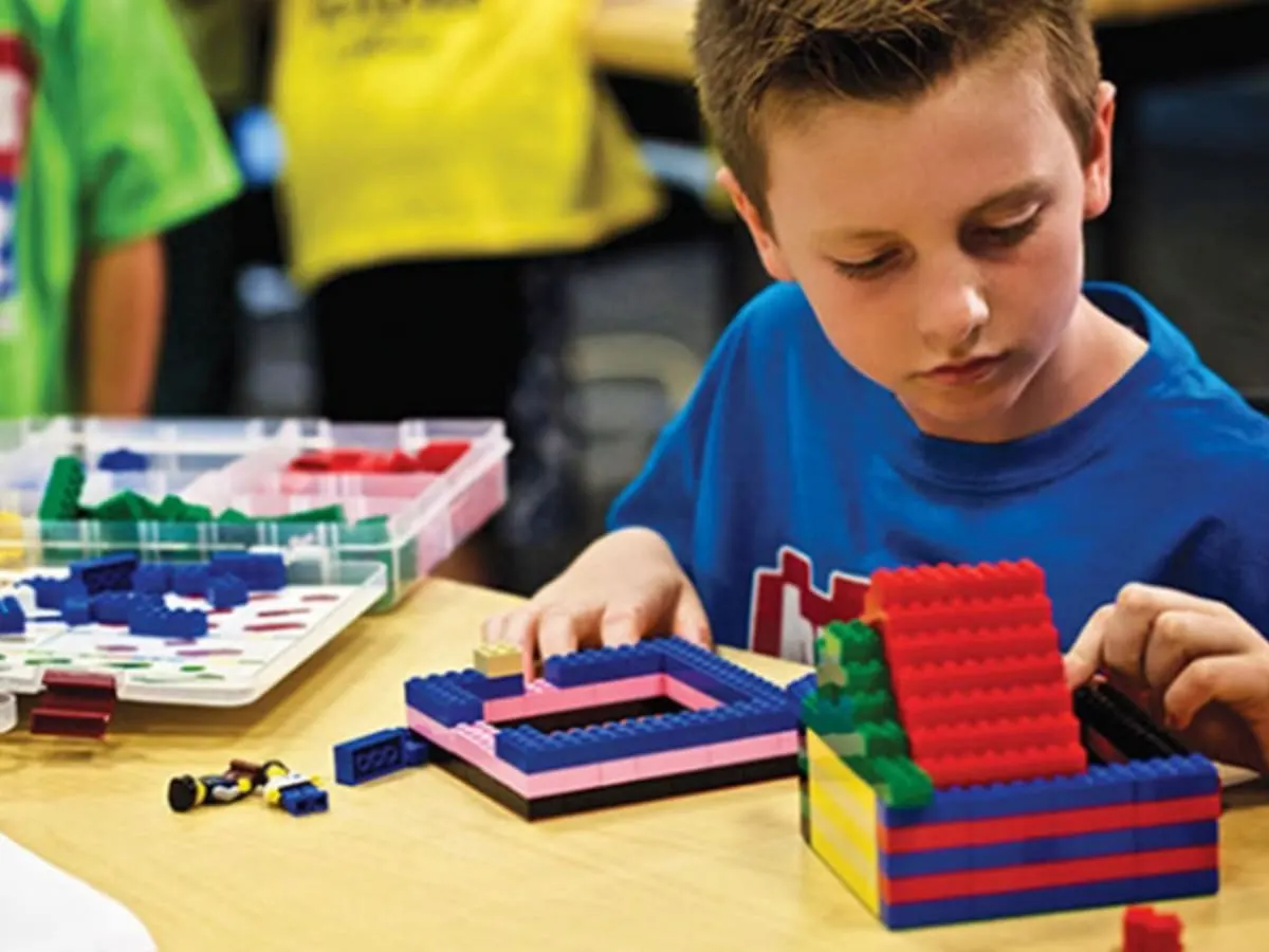 Un enfant est concentré à assembler des Legos.