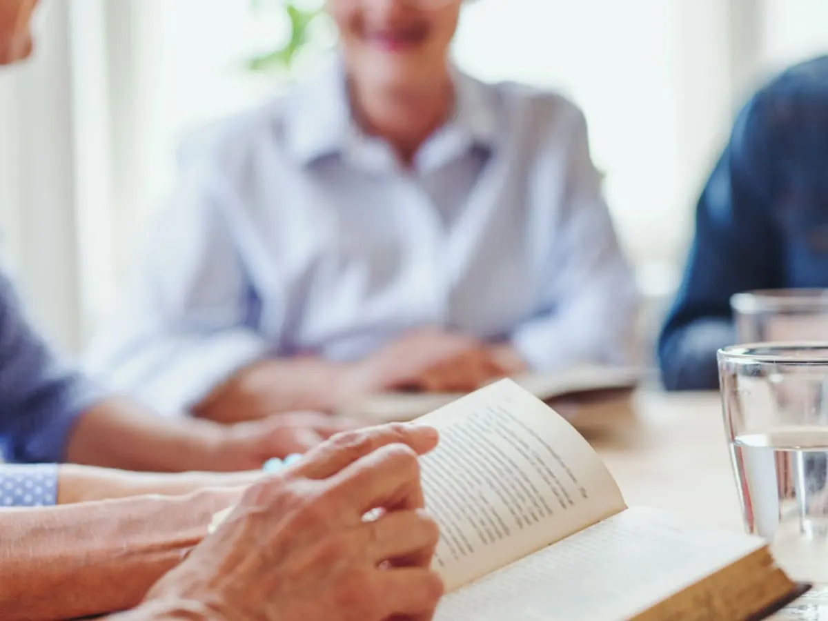 Des personnes assises autour d'une table tenant un livre ouvert dans leurs mains.