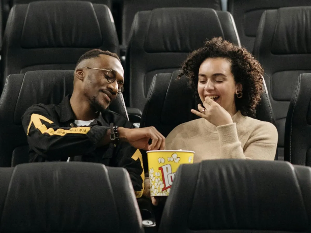 Photo de deux personnes dans des sièges de cinema mangeant du popcron