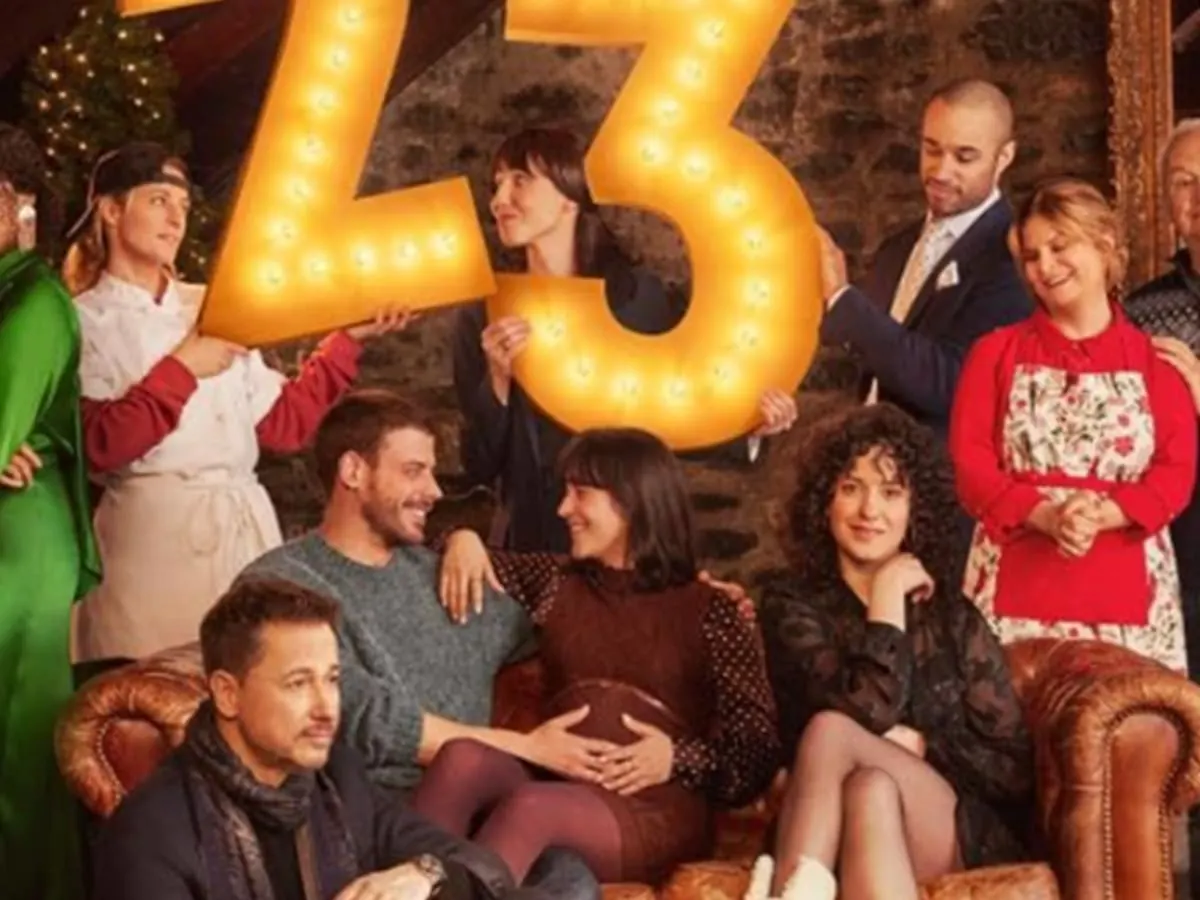 Une famille réunie dans un décor festif, qui pose autour de grands chiffres «23» lumineux.