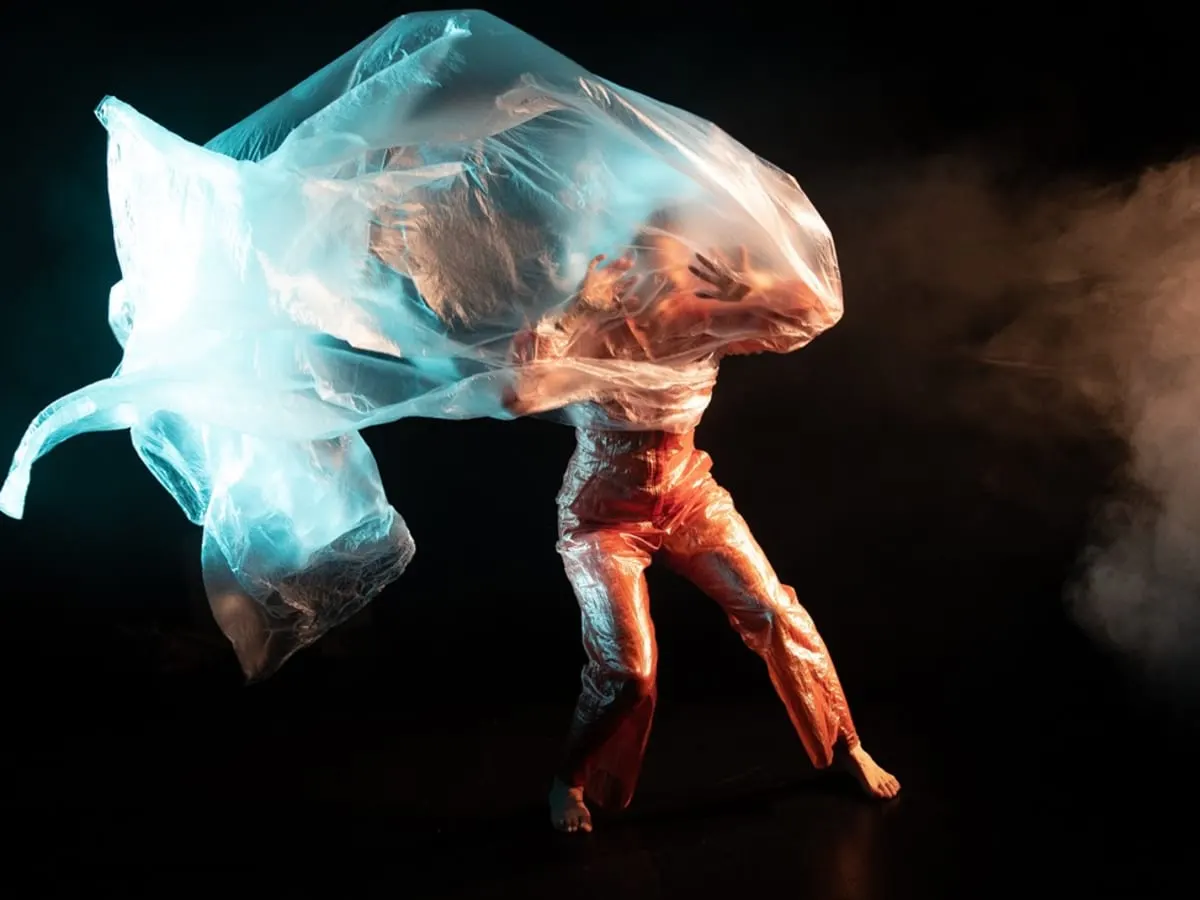 Une personne qui danse semble prise dans un grand morceau de plastique.