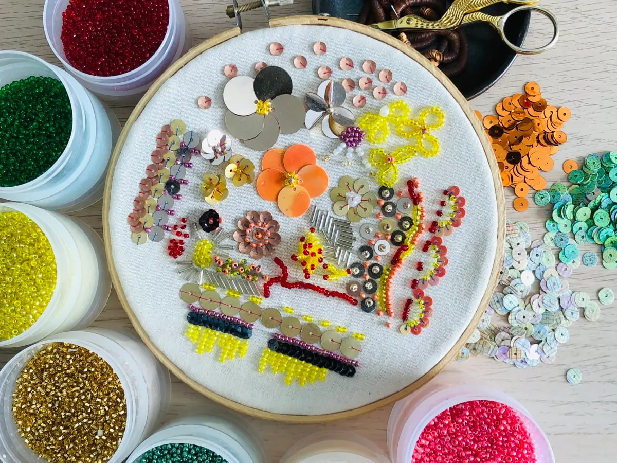 Une photo de fleures en perlage entourés de bols de perles colorées