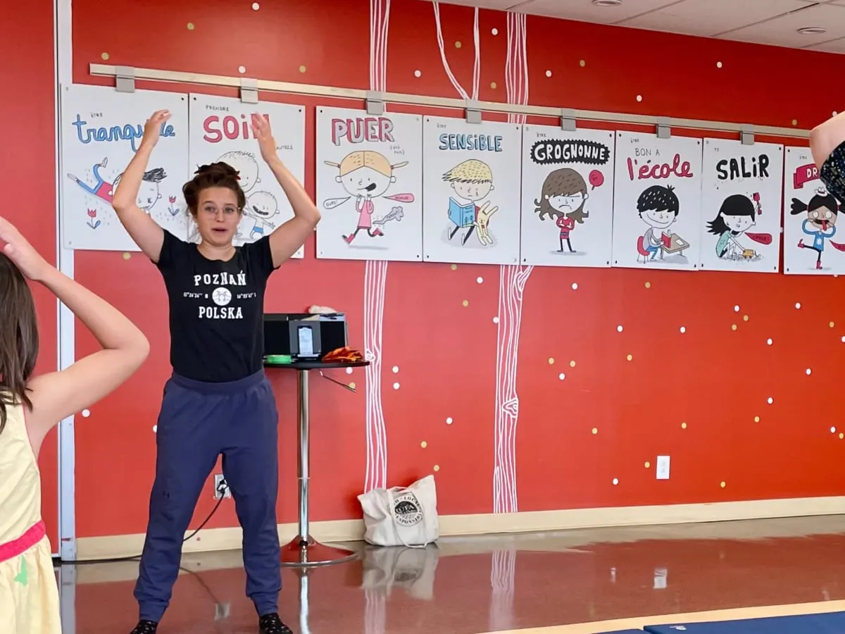 Une animatrice fait des gestes avec ses bras devant quelques personnes.