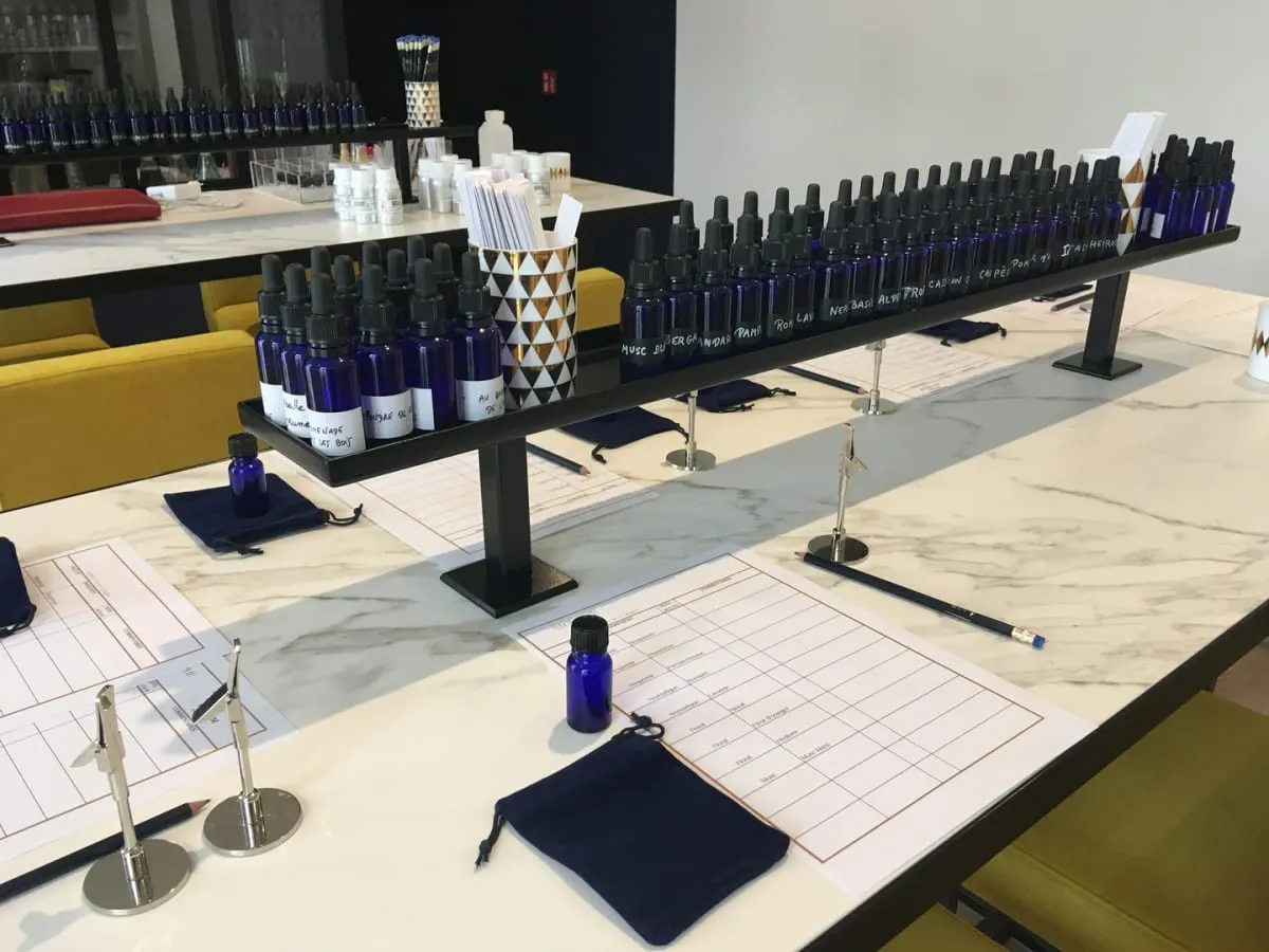 Photographie de la table de travail de l’atelier, incluant de nombreux flacons d’huiles essentielles.