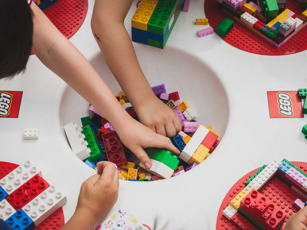 Mains d'enfants pigeant dans une plate forme creuse remplie de Legos.