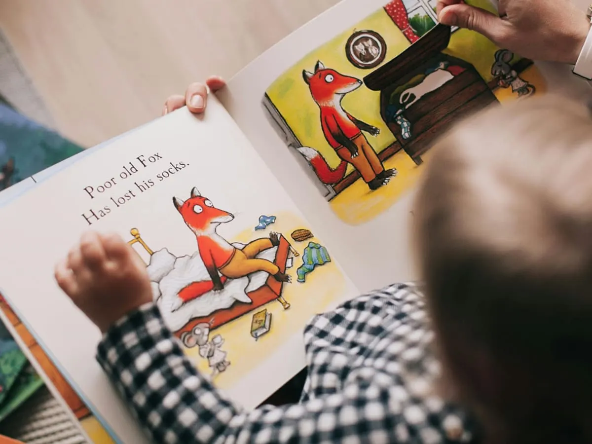 Jeune enfant qui regarde un livre illustré.