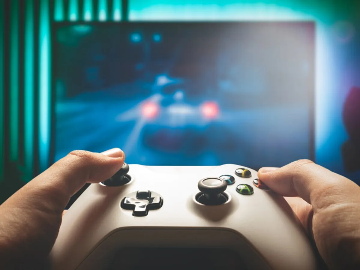 Photo d'une personne tenant une manette de jeux devant un écran