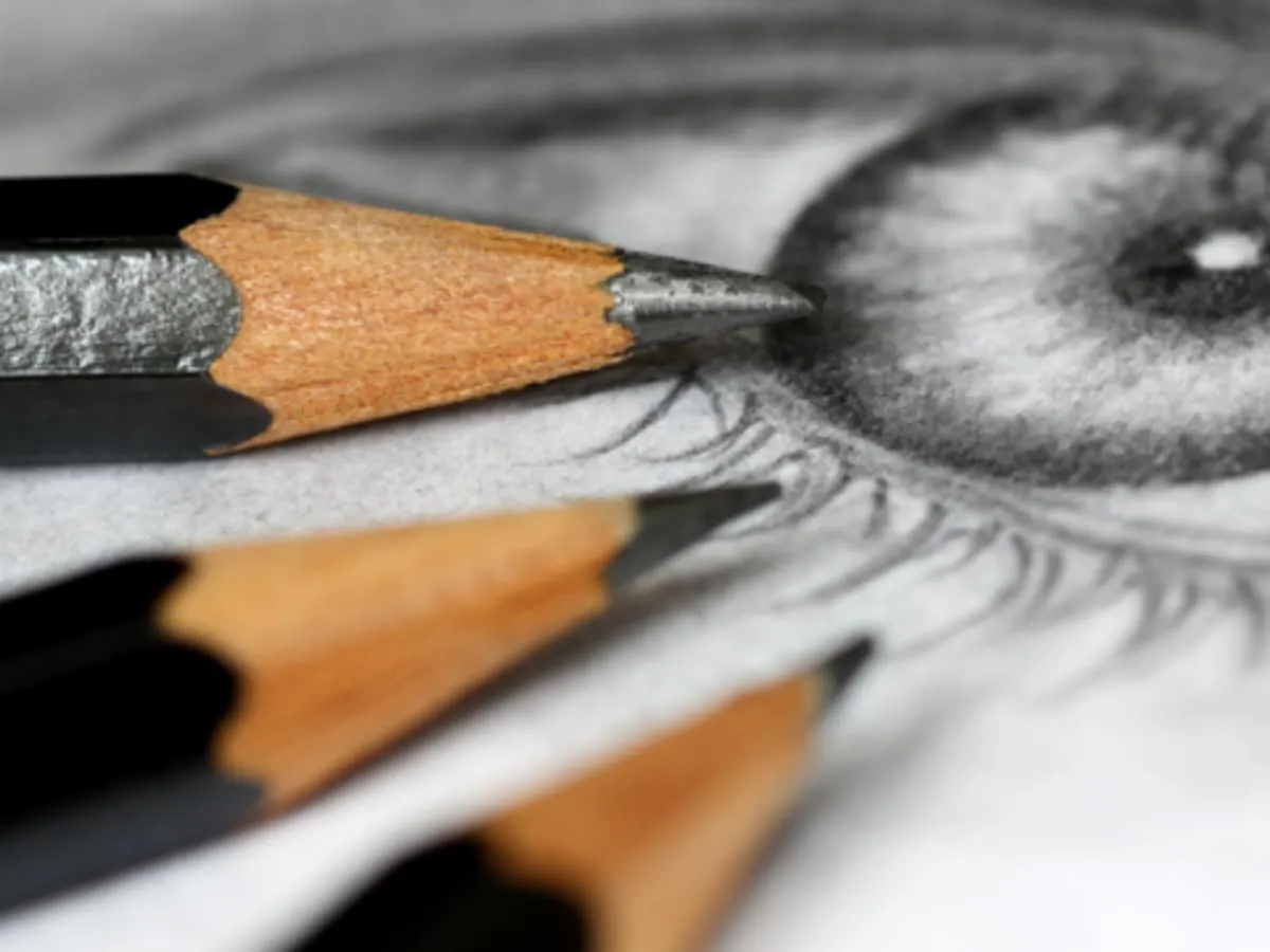 Trois crayons posés sur le dessin d'un oeil.