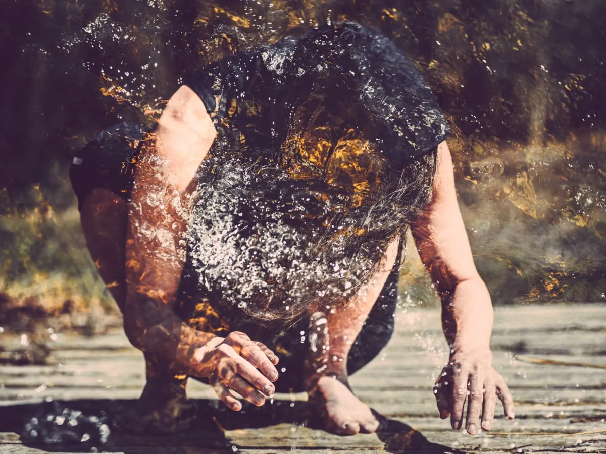 image d'un homme accroupie au sol la tête penché avec des couleurs éparpillés de manière confetti sur l'image.