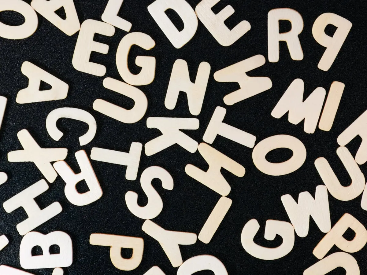 Lettres de l'alphabet en bois sur fond noir.